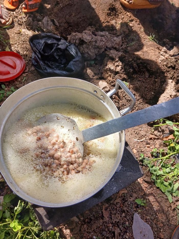 A large pot of food cooking over an outdoor fire