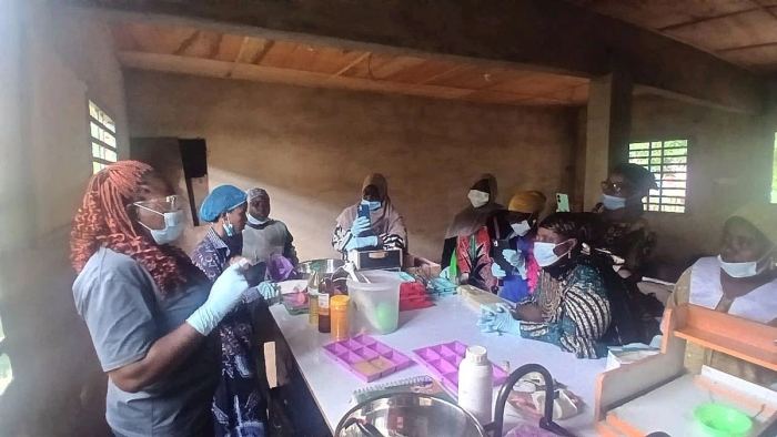 A soap-making trainer demonstrating to women in gloves and masks