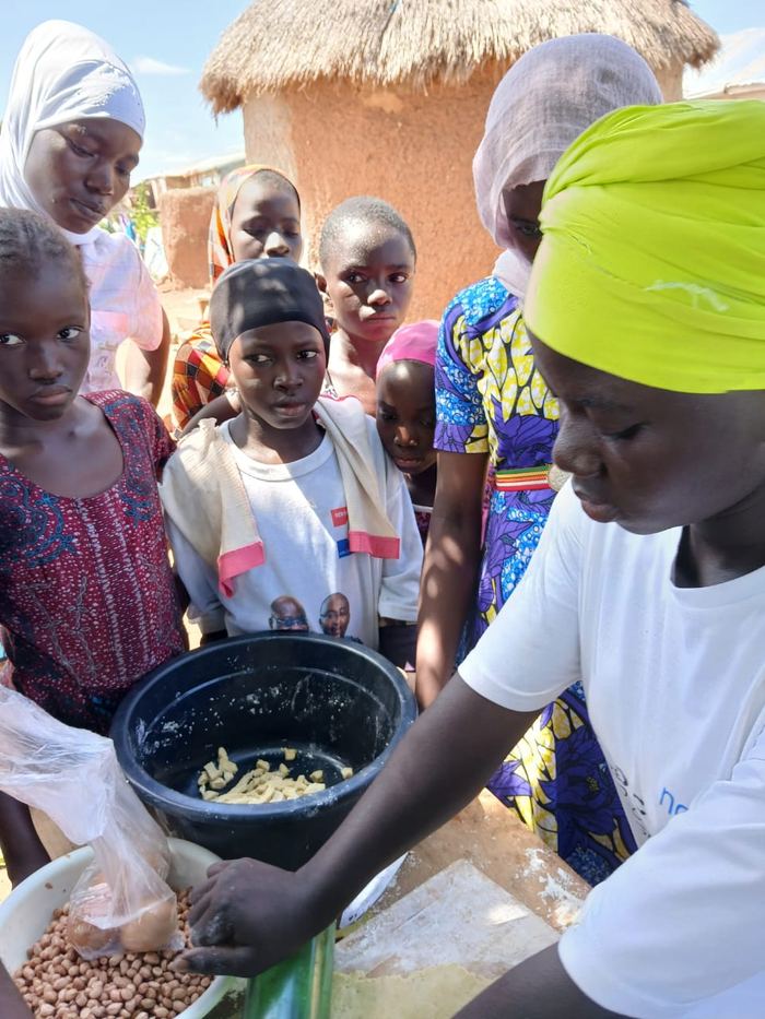 A woman lifting a bowl of food surrounded by schoolchildren