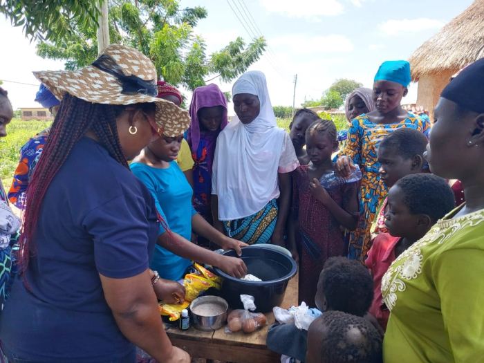 Women serving a meal from a table to a crowd of children