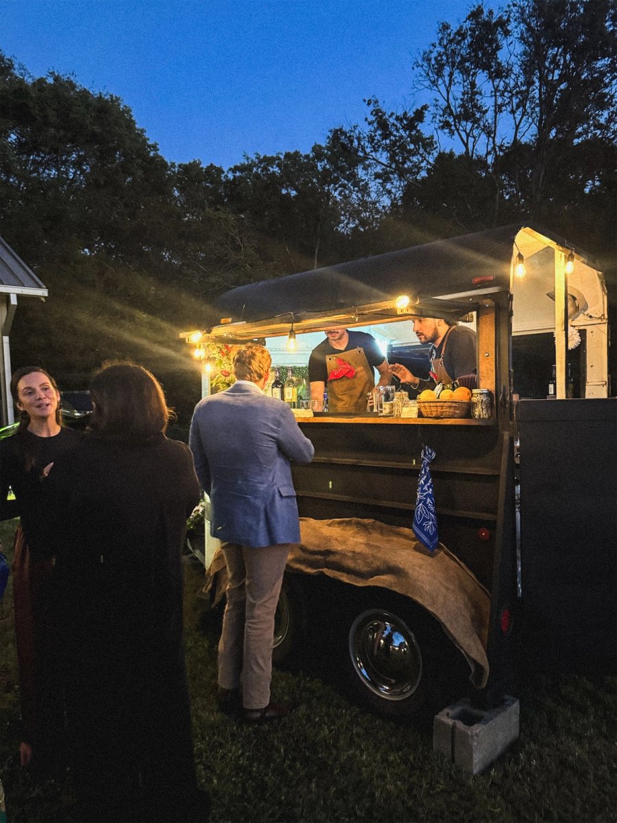 The Howdy trailer at dusk with string lights, bartenders serving guests at the outdoor window.