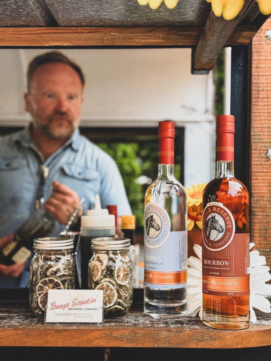 Two Nelson's Green Brier whiskey bottles on the trailer's bar, Dan out of focus behind them in a denim shirt.