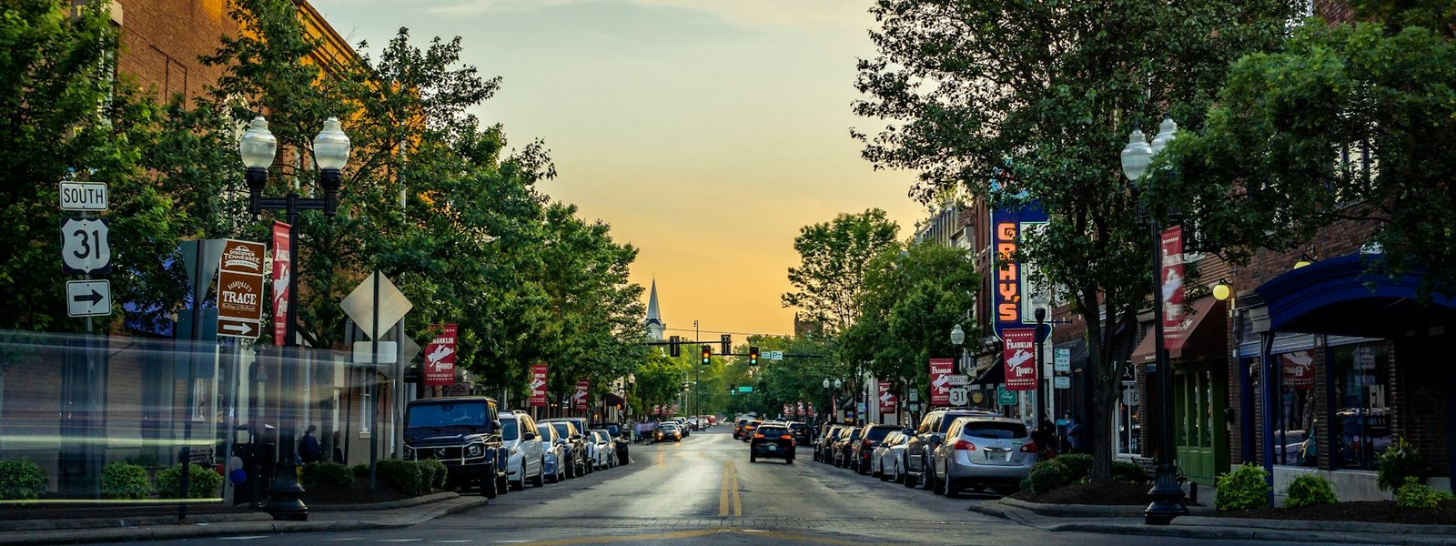 Downtown Franklin, Tennessee at dusk. Historic Main Street storefronts line both sides of the road.