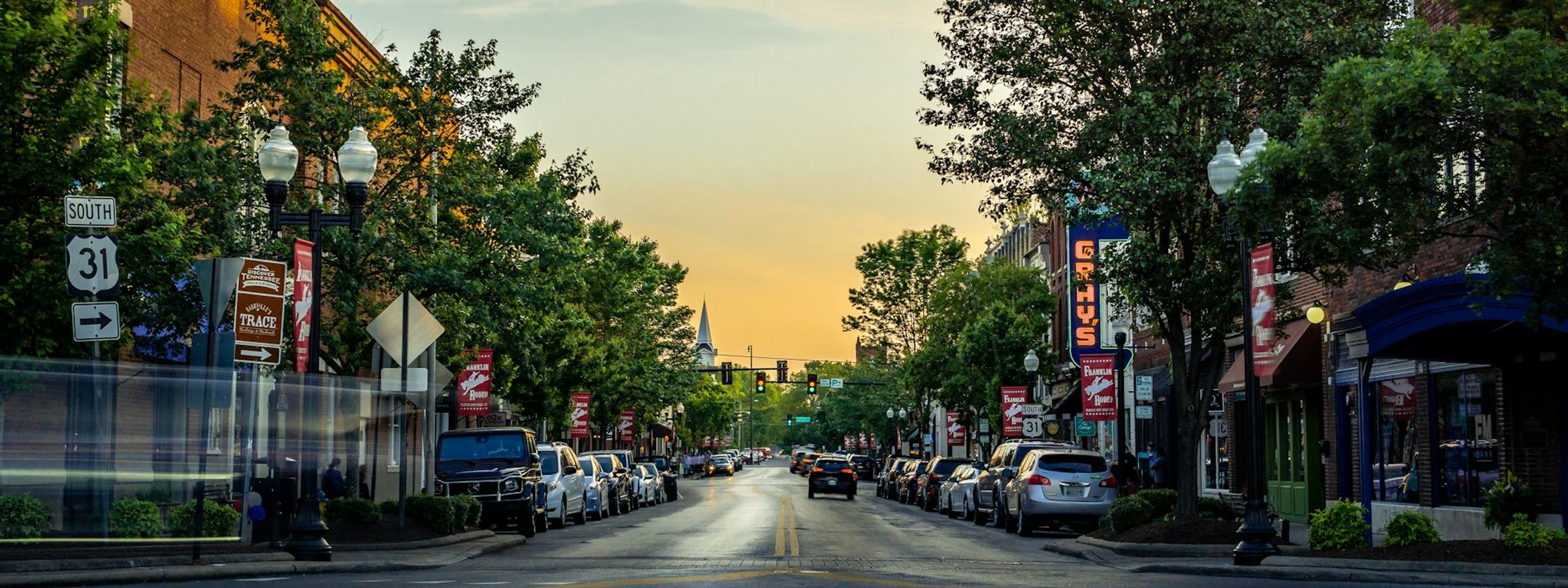 Downtown Franklin, Tennessee at dusk. Historic Main Street storefronts line both sides of the road.