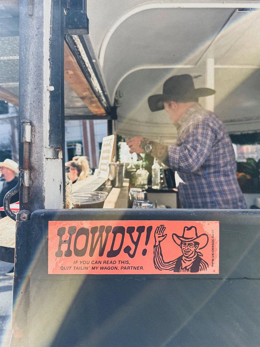 A 'Howdy! Quit tailin' my wagon, partner' sticker on the back of the trailer, a cowboy silhouette through the window.