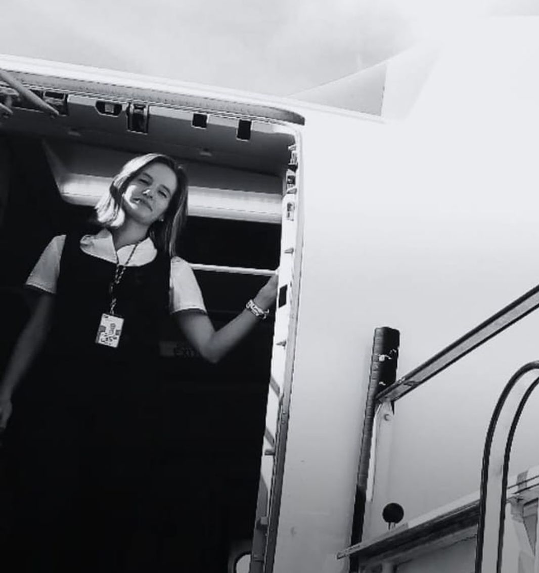 A Anica de uniforme, à porta do avião, no topo da escada