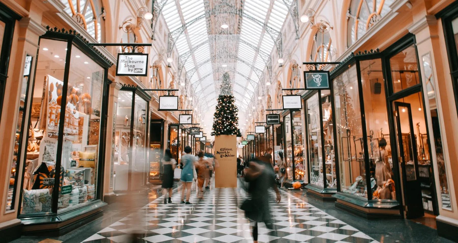 A bustling arcade passage with boutique storefronts, shoppers, and holiday decorations—the kind of high-traffic customer experience that Dancing Pels growth marketing helps service businesses attract.