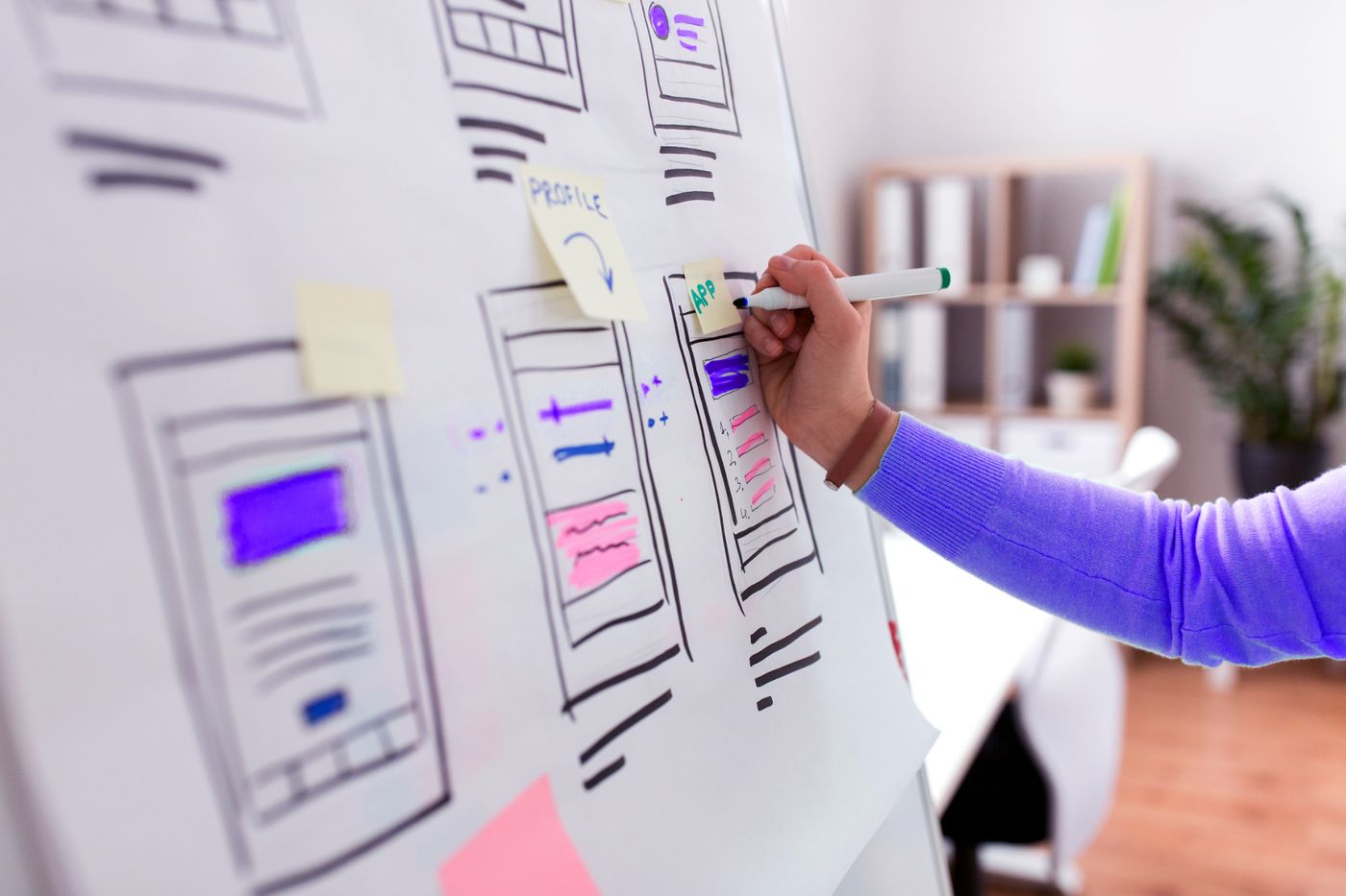 A designer's hand sketches website wireframe layouts on a whiteboard during a Dancing Pels project planning session.