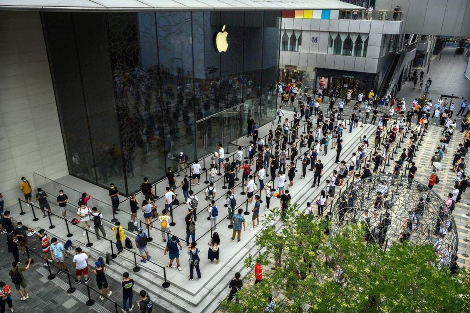 Aerial view of a busy urban plaza with crowds of people moving through a modern public space near an Apple Store, illustrating audience engagement and customer flow.