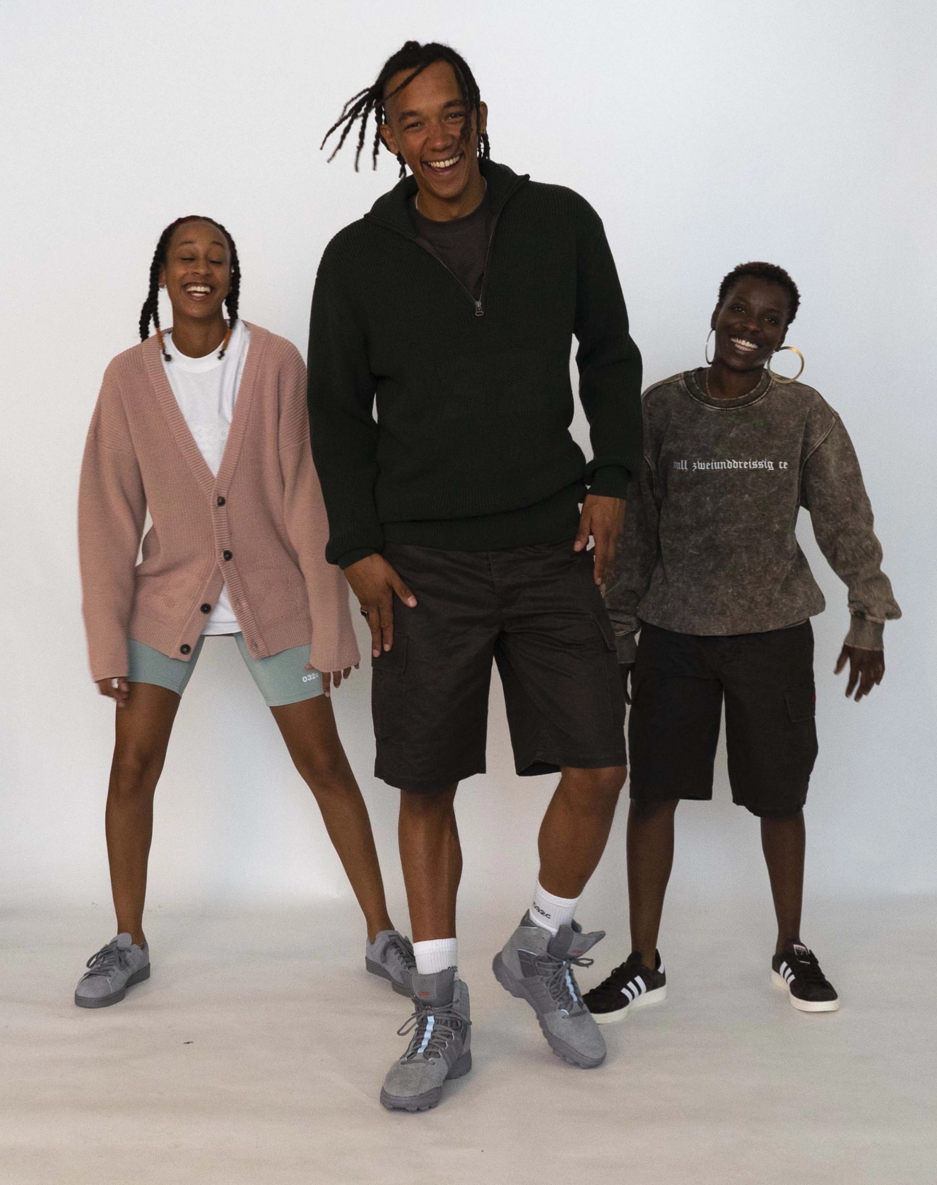Libell, Buyegi and Mariama dazzle with bright smiles! Libell wears the 032c LoveSexDreams Knit Cardigan, and longsleeve t-shirt in white with neoprene shorts in mint. Buyegi wears the Knit Troyer in olive and Cargo Shorts, with the 032c x adidas Originals GSG-9High Top Sneaker. Mariama wears the "null zweiunddreißig ce" crewneck in acid wash brown with Cargo Shorts.