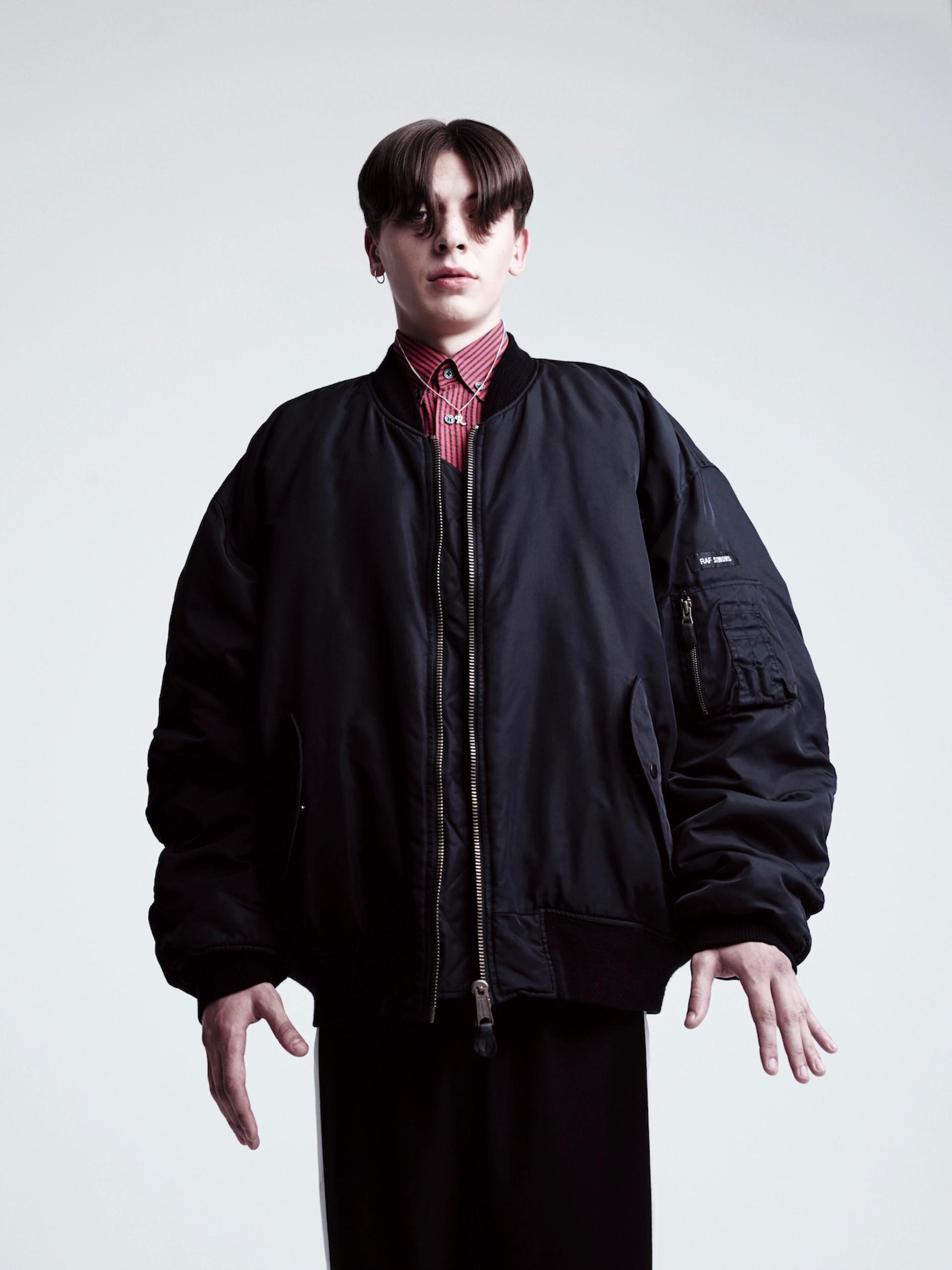LANDER: nylon bomber jacket, cotton shirt, polyester track pants with inserts: RAF SIMONS S/S 2000; silver necklace with silver 'R-initial' pendant and silver earring: RAF SIMONS A/W 2003/2004