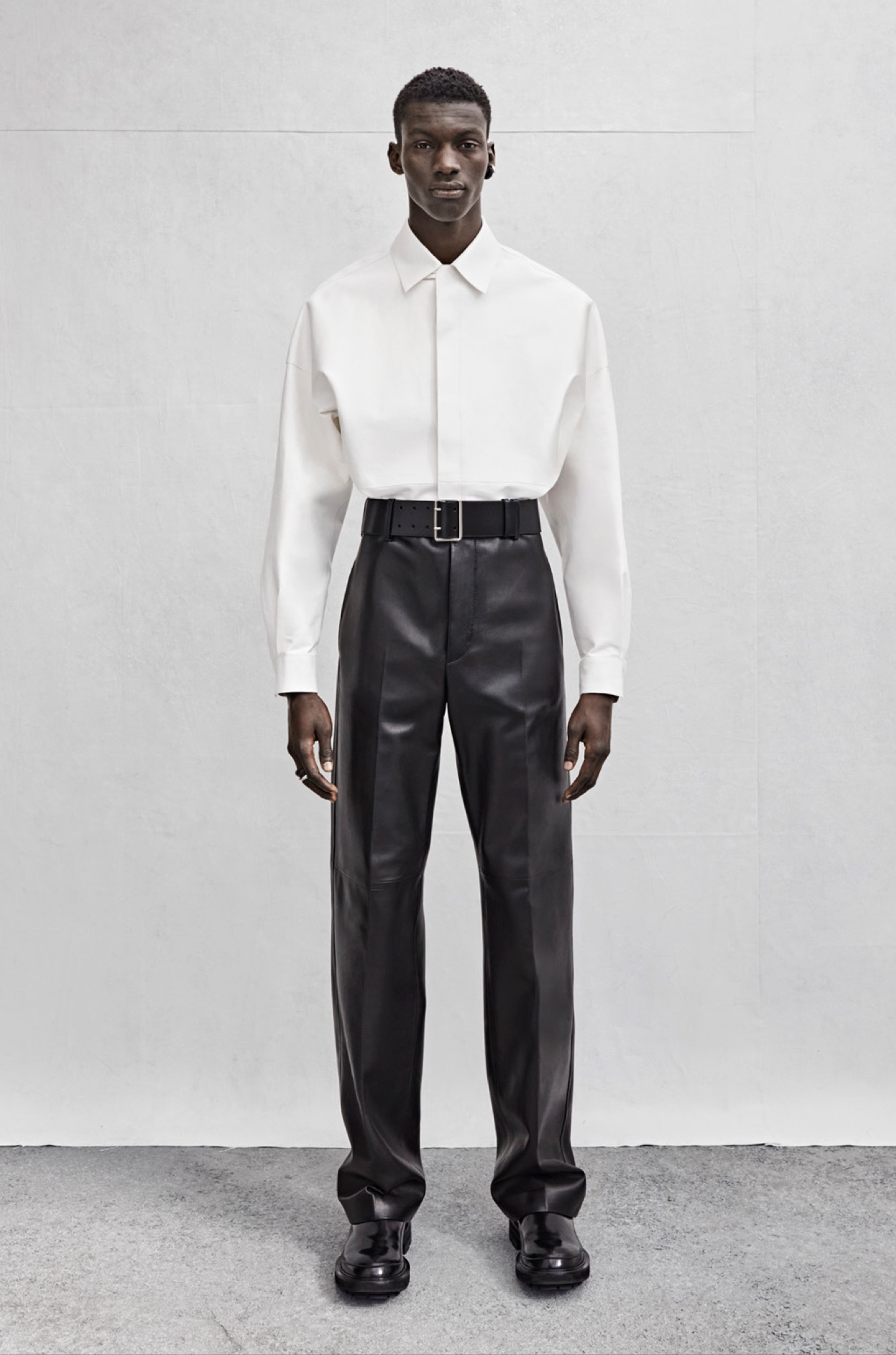 A drop shoulder shirt in ivory leather and wide-legged trousers in black leather.