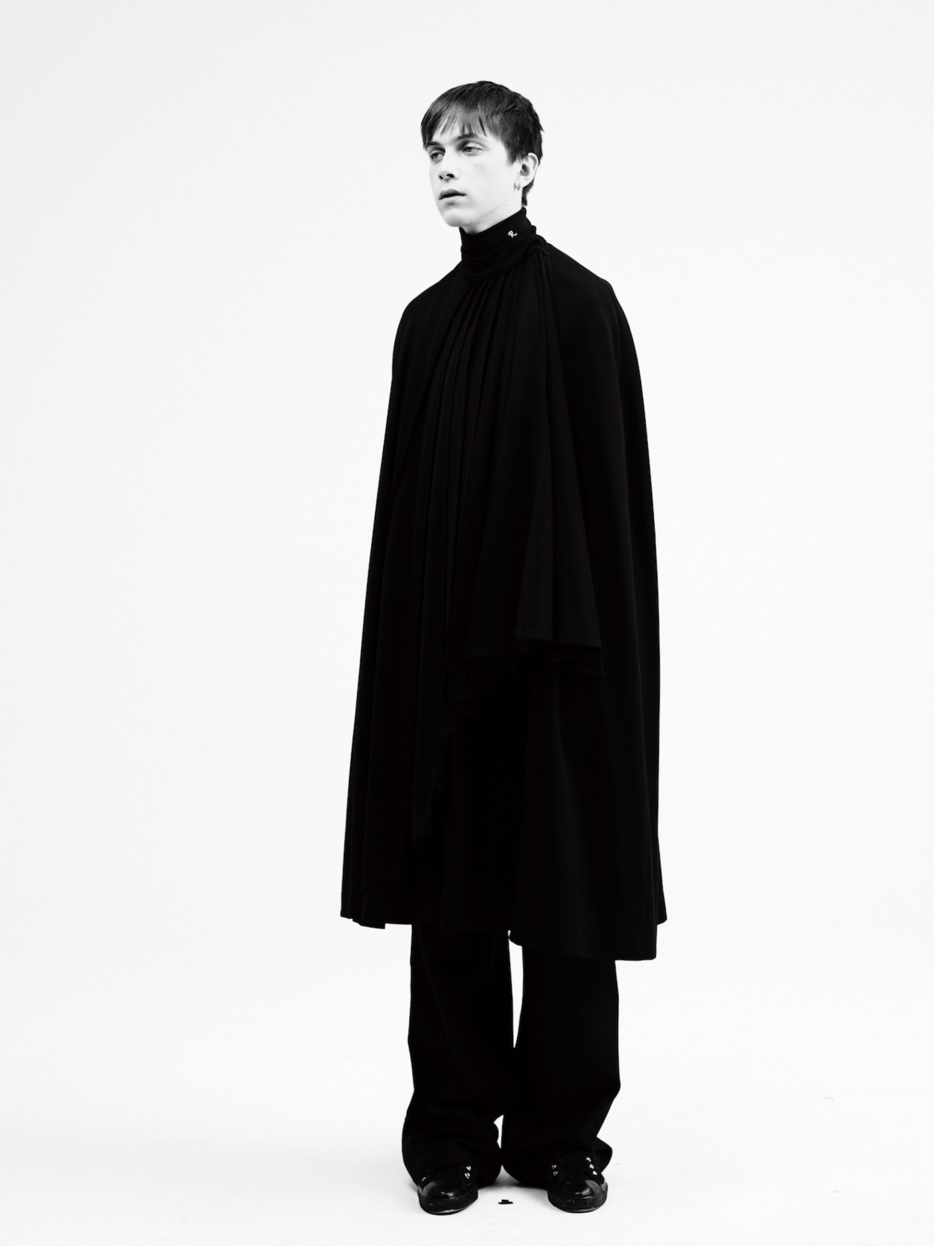 MATEO: wool pleated cape, polyester turtle neck with 'R' initial embroidery, wool jogging pants, customized 'All Stars': RAF SIMONS A/W 1999/2000; silver earring: RAF SIMONS A/W 2003/2004