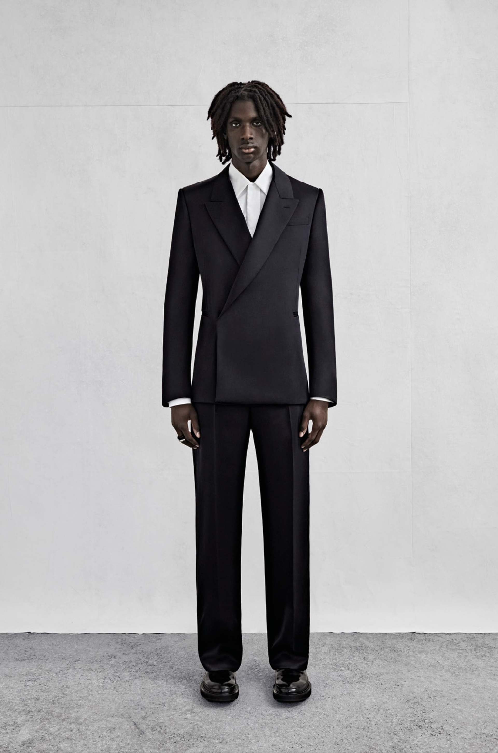 A double-breasted tailored jacket in black fluid twill, a shirt in white cotton poplin and wide-legged trousers in black fluid twill.