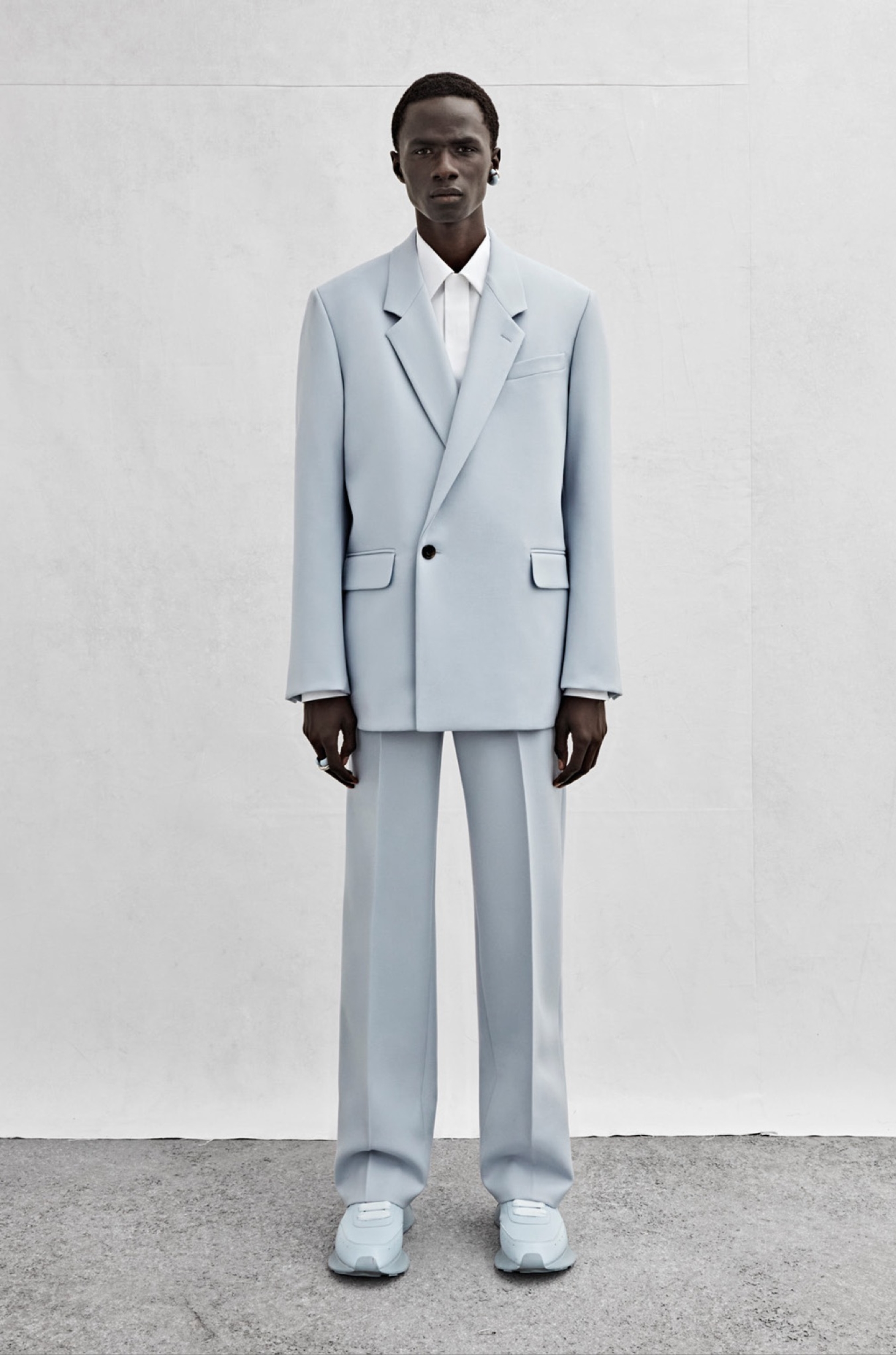 An oversized double-breasted jacket in powder blue wool, a shirt in white cotton poplin and wide-legged trousers in powder blue wool.
