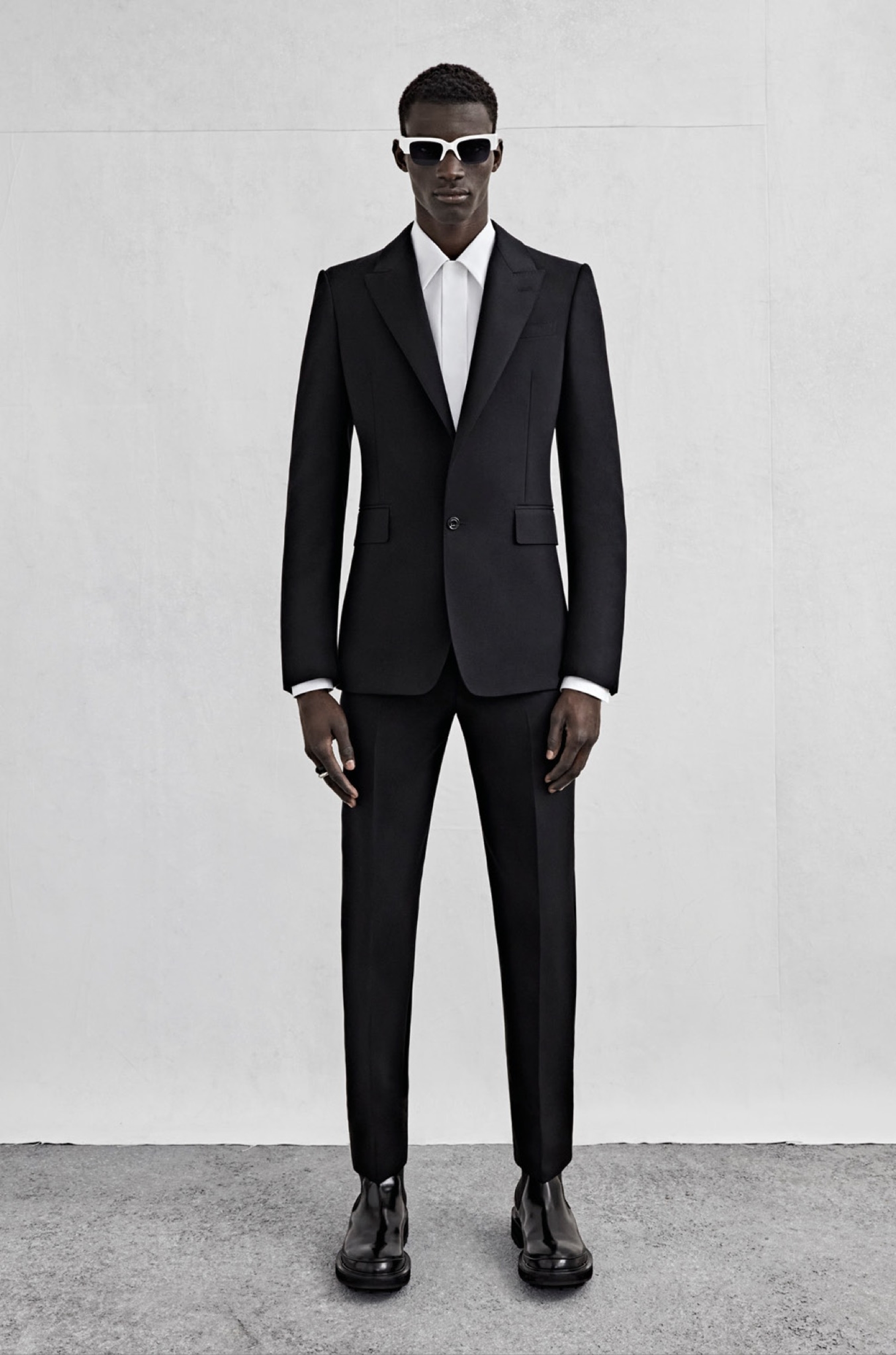 A single-breasted tailored jacket in black wool gabardine, a shirt in white cotton poplin and cigarette trousers in black wool gabardine.