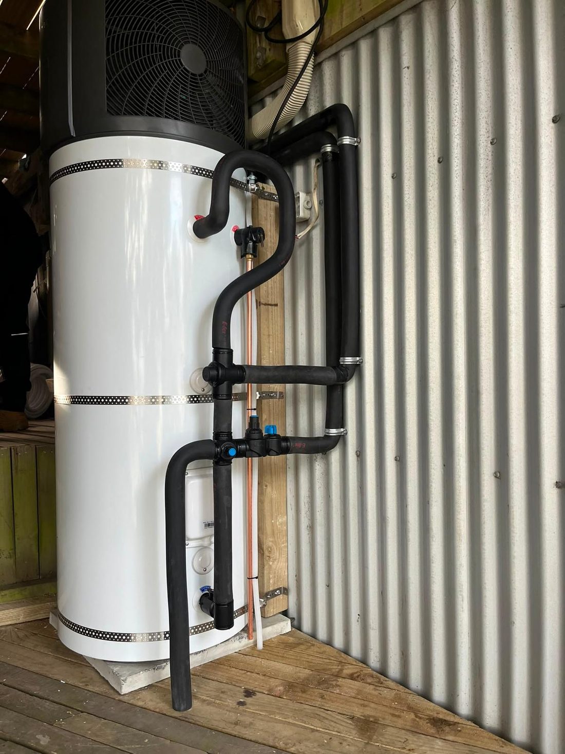 Heat pump hot water cylinder with insulated pipework installed inside a utility shed