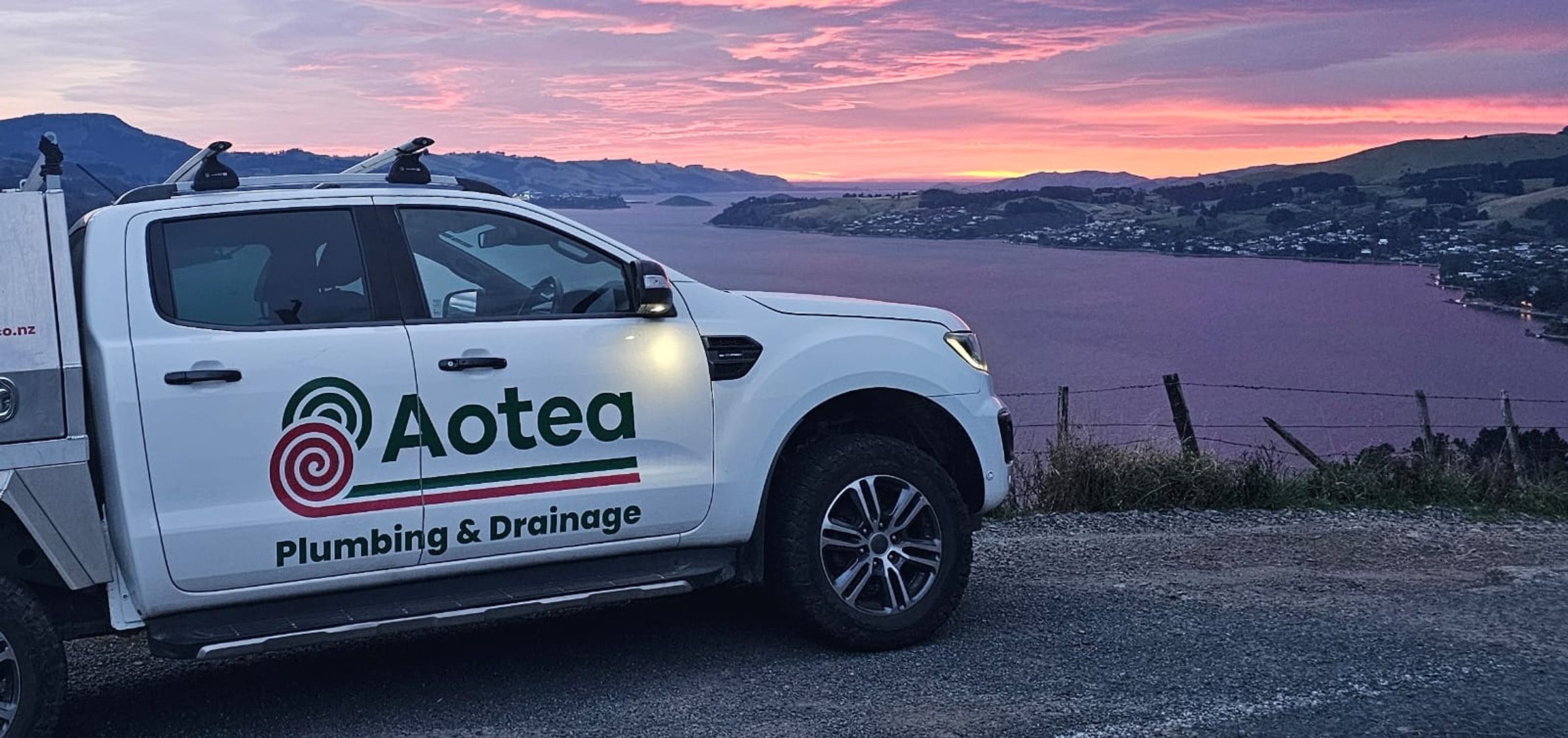 Aotea Plumbing & Drainage service ute overlooking Otago Harbour at sunset
