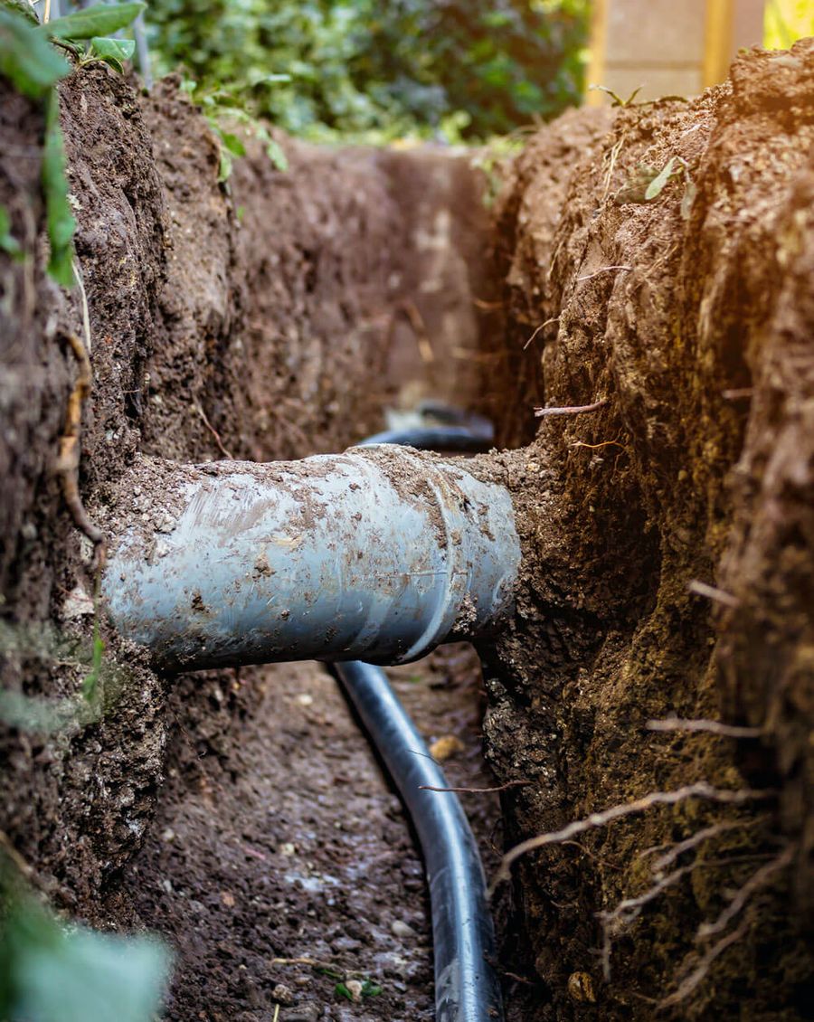 Exposed underground water and drainage pipes in an excavated trench