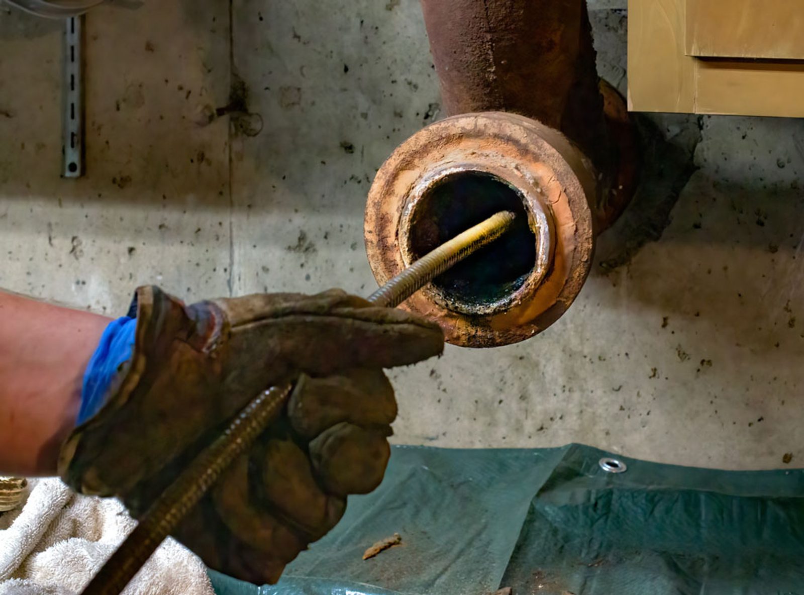 Plumber feeding a CCTV inspection camera into a drain pipe to assess a blockage