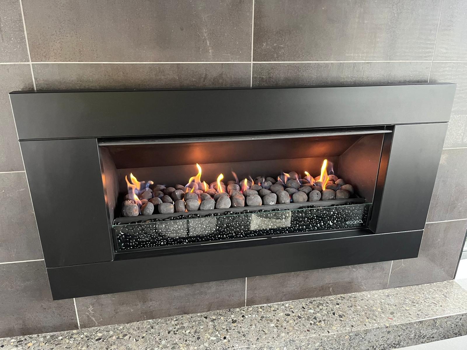 Modern built-in gas fireplace with a black frame and decorative stones