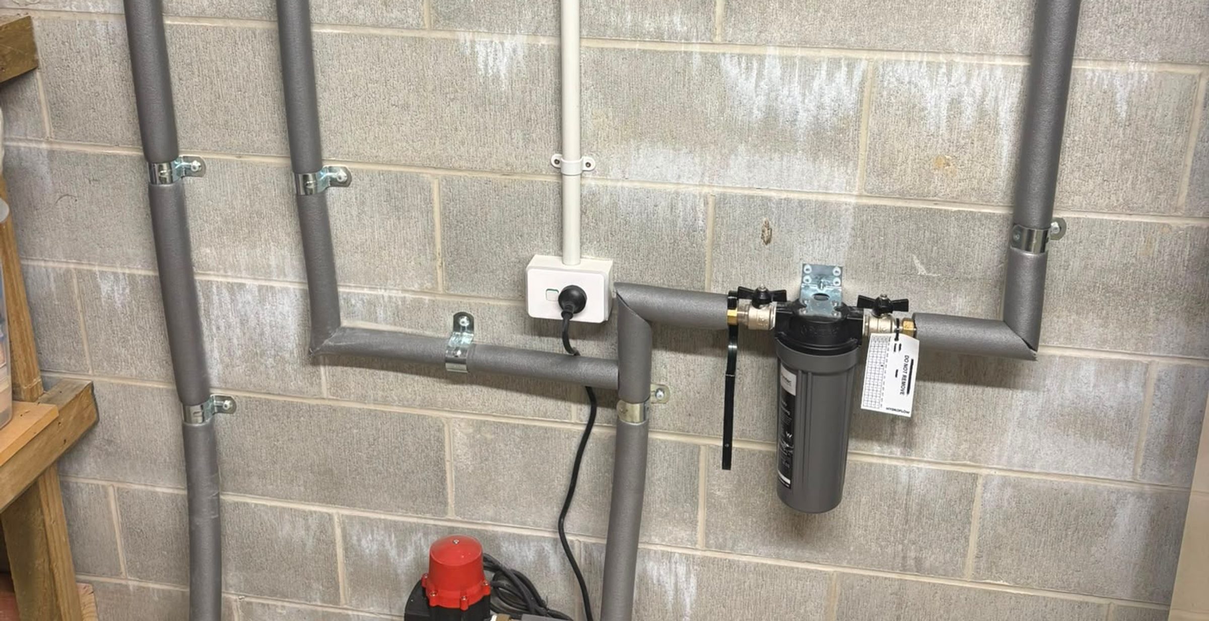 Whole-house water filtration system with pump and wall-mounted pipework