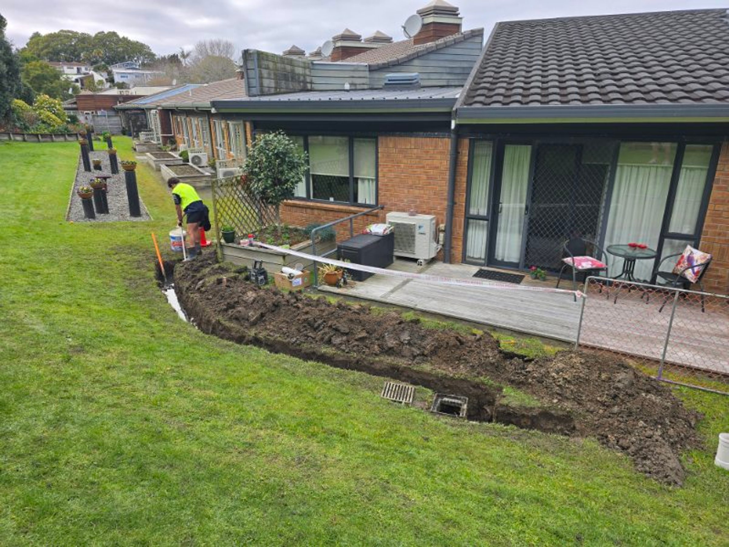 Aotea drainlayer installing residential drainage beside a brick home