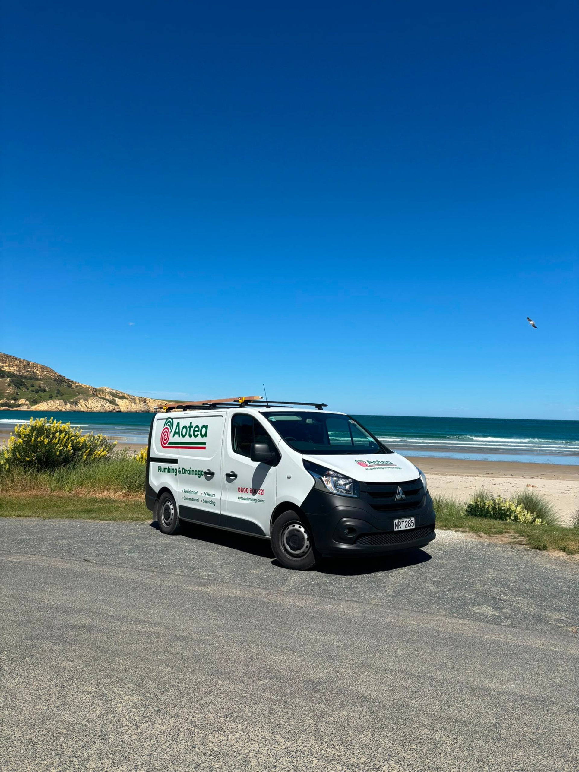 Aotea Plumbing & Drainage service van parked beside a New Zealand beach