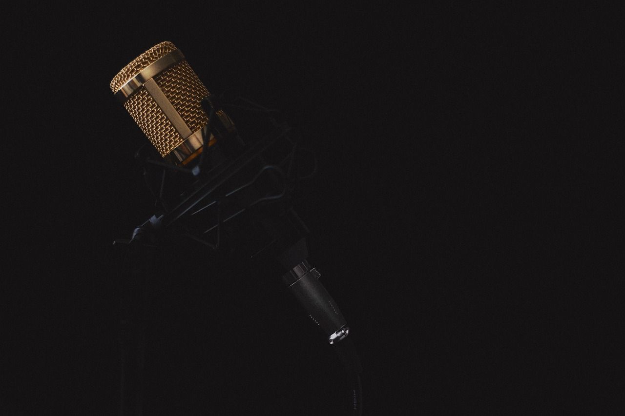 Podcaster merekam podcast menggunakan setup minimal di dalam booth rumahan dengan mikrofon USB dan headphone