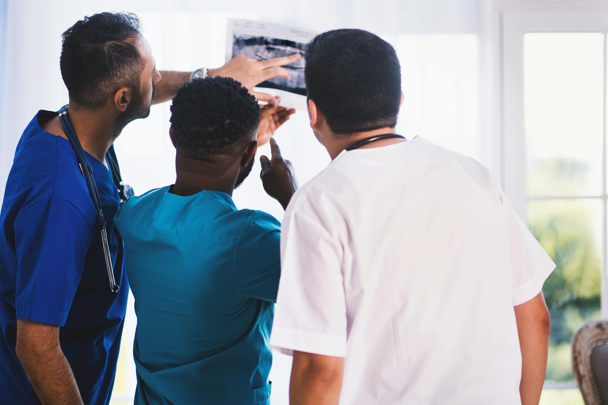 Three clinicians reviewing an X-ray together by a window