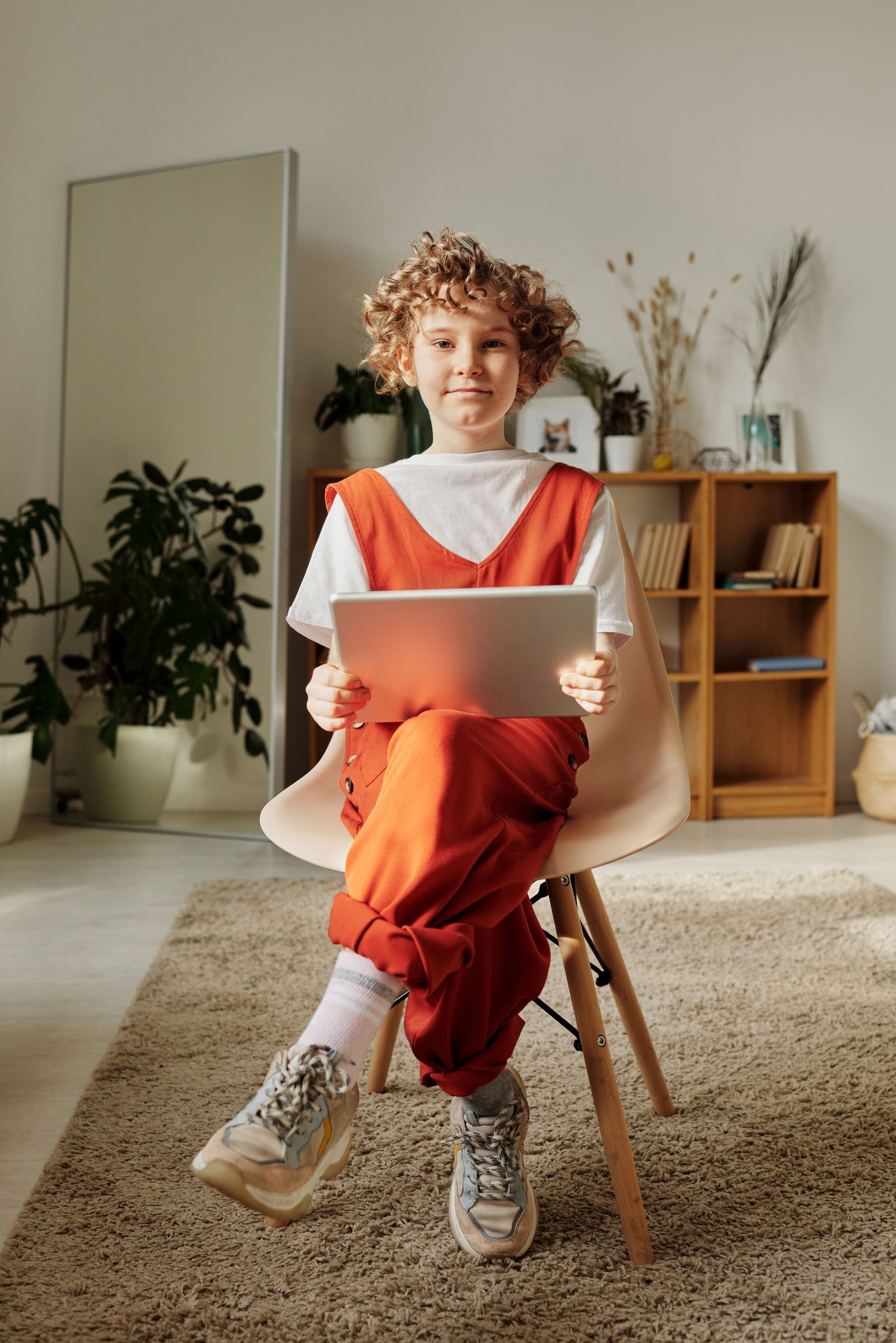 A child sitting on a chair at home concentrating on a tablet