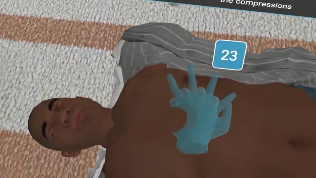 A hand placed on the patient’s chest in the CPR simulation, with the compression counter at 23
