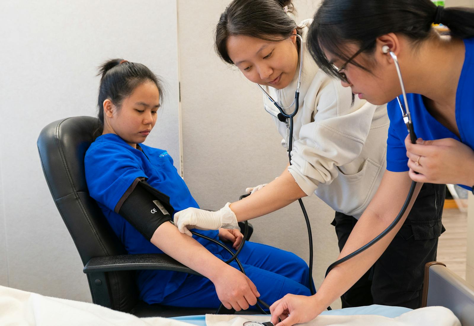 Two students taking a classmate’s blood pressure during vital signs practice