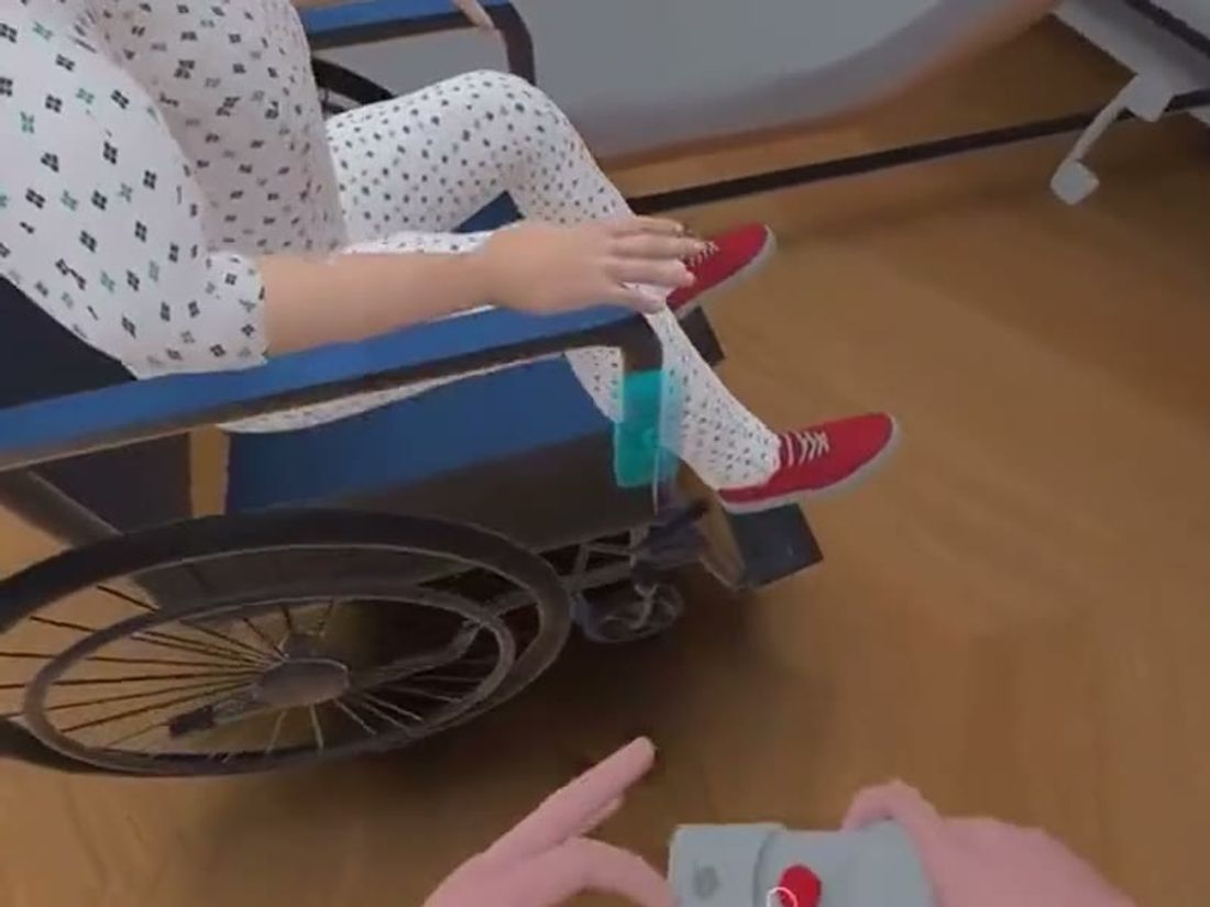 A virtual resident seated in a wheelchair beside the bed, seen from the student’s view in the VR headset