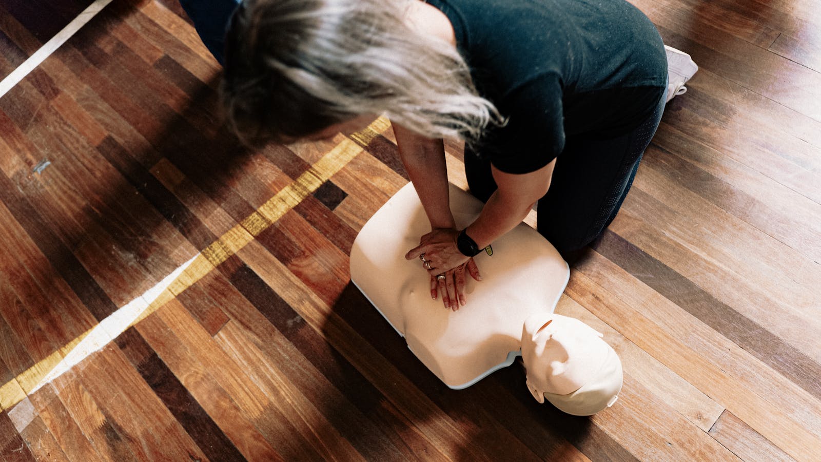 Hands demonstrating chest compressions on a resuscitation training manikin