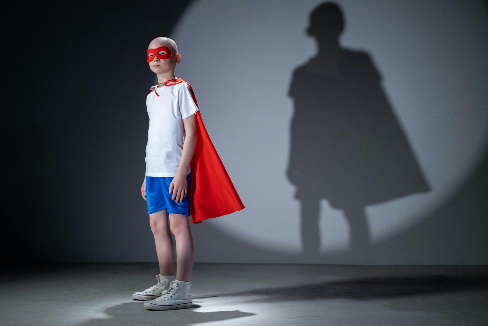 A child wearing a cape posing confidently, like a small superhero