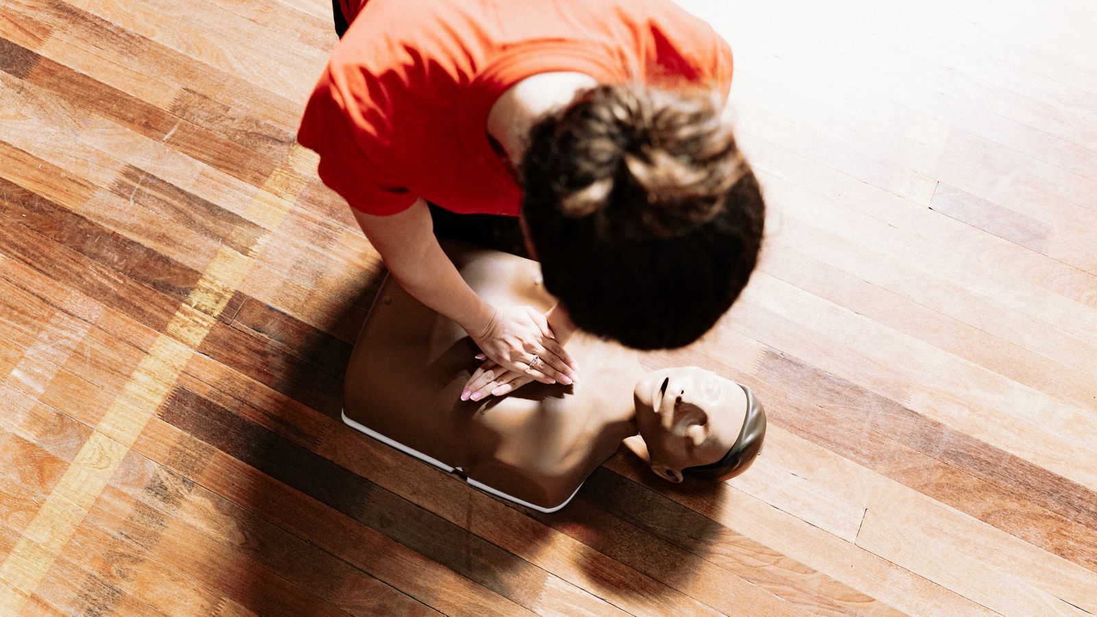 An instructor guiding a student through resuscitation practice on a training manikin