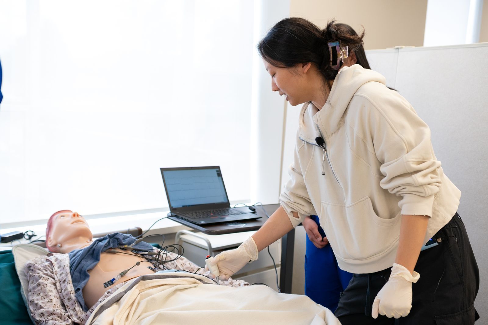 A healthcare student practising a procedure on a training manikin in a simulation lab