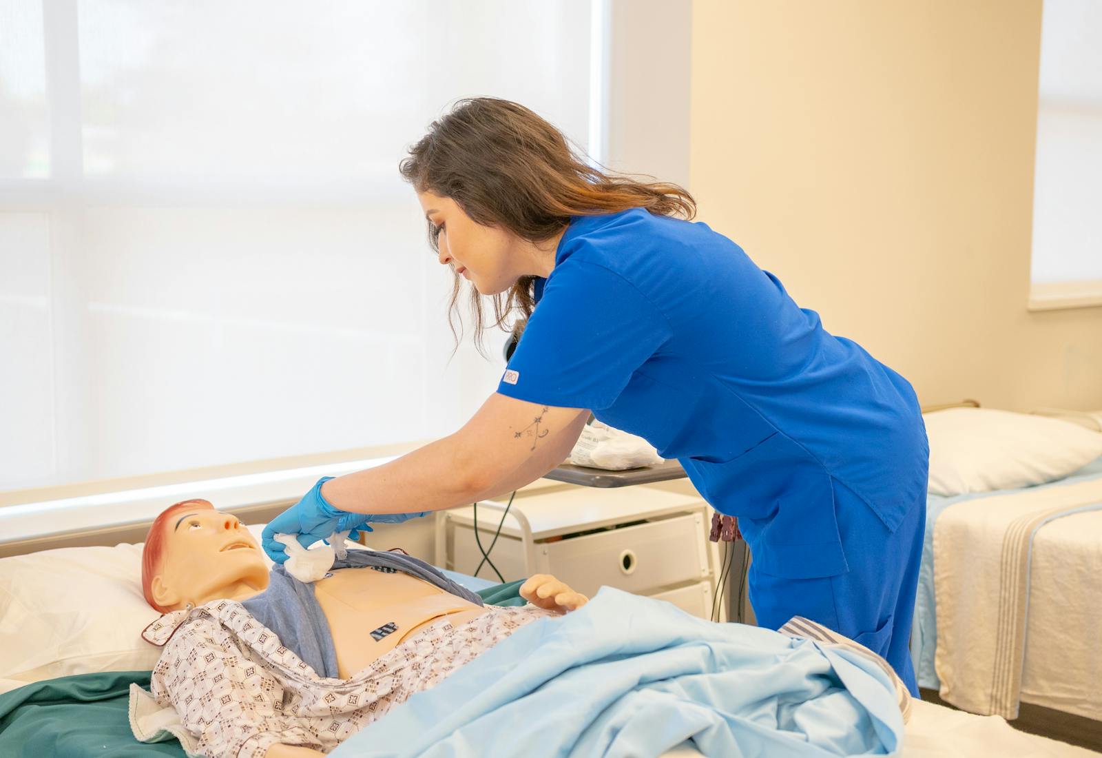 A nursing assistant student practicing a bedside care skill on a manikin in the skills lab