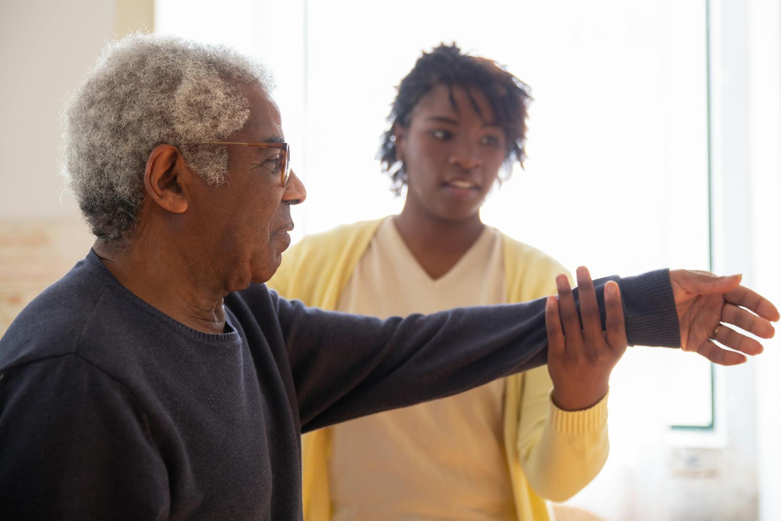 A caregiver helping an older person with a mobility exercise