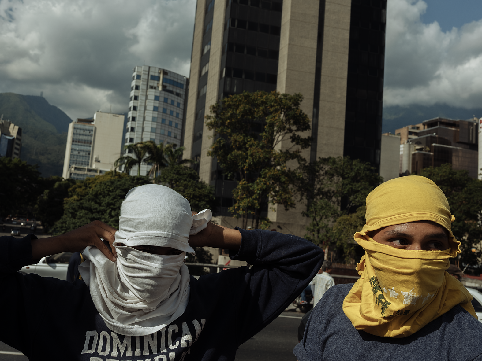 two men with faces covered by tshirts, in venezuela