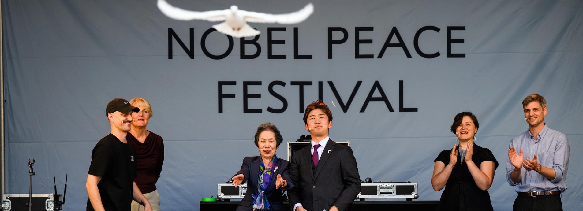 Release of the peace dove. 6 people on stage while crowd is watching.