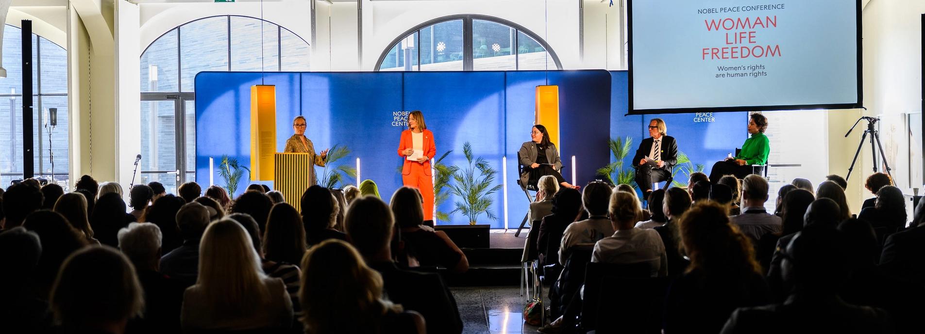 Fra Nobel Peace Conference 2024. Man ser scenen og publikum bakfra.