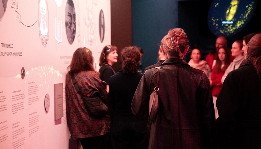 Guided tour in a exhibition with people listening and watching the guided tour.