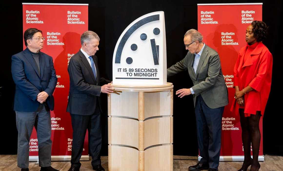 doomsday clock being tuned by people on a stage.