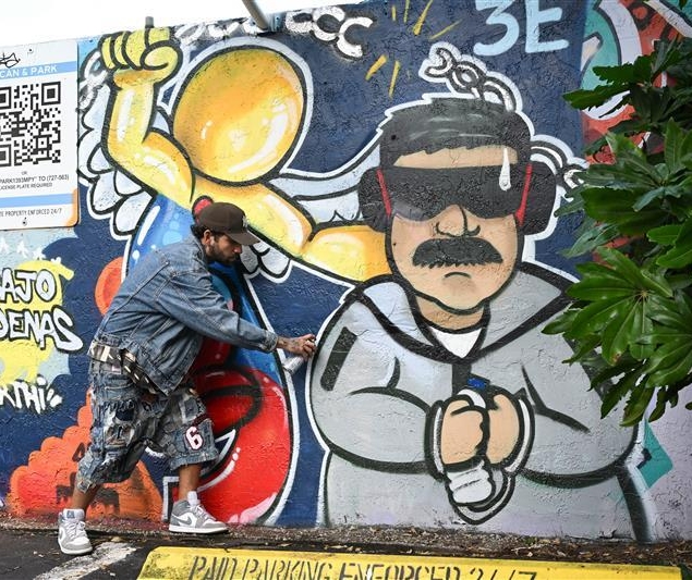 A man with grafitti of maduro in handcuffs.