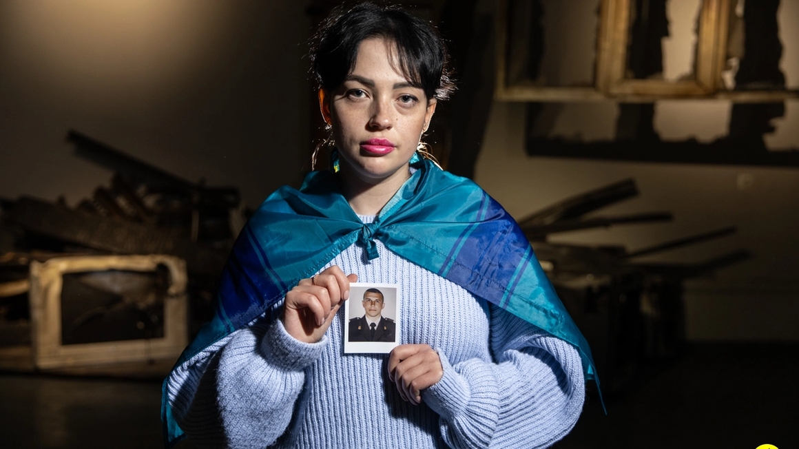 a woman holding a photo of a millitary man.
