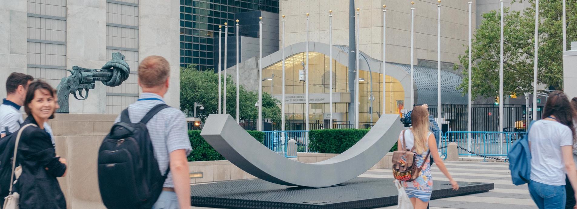 The peace bench, people walking past, american flag in the background.