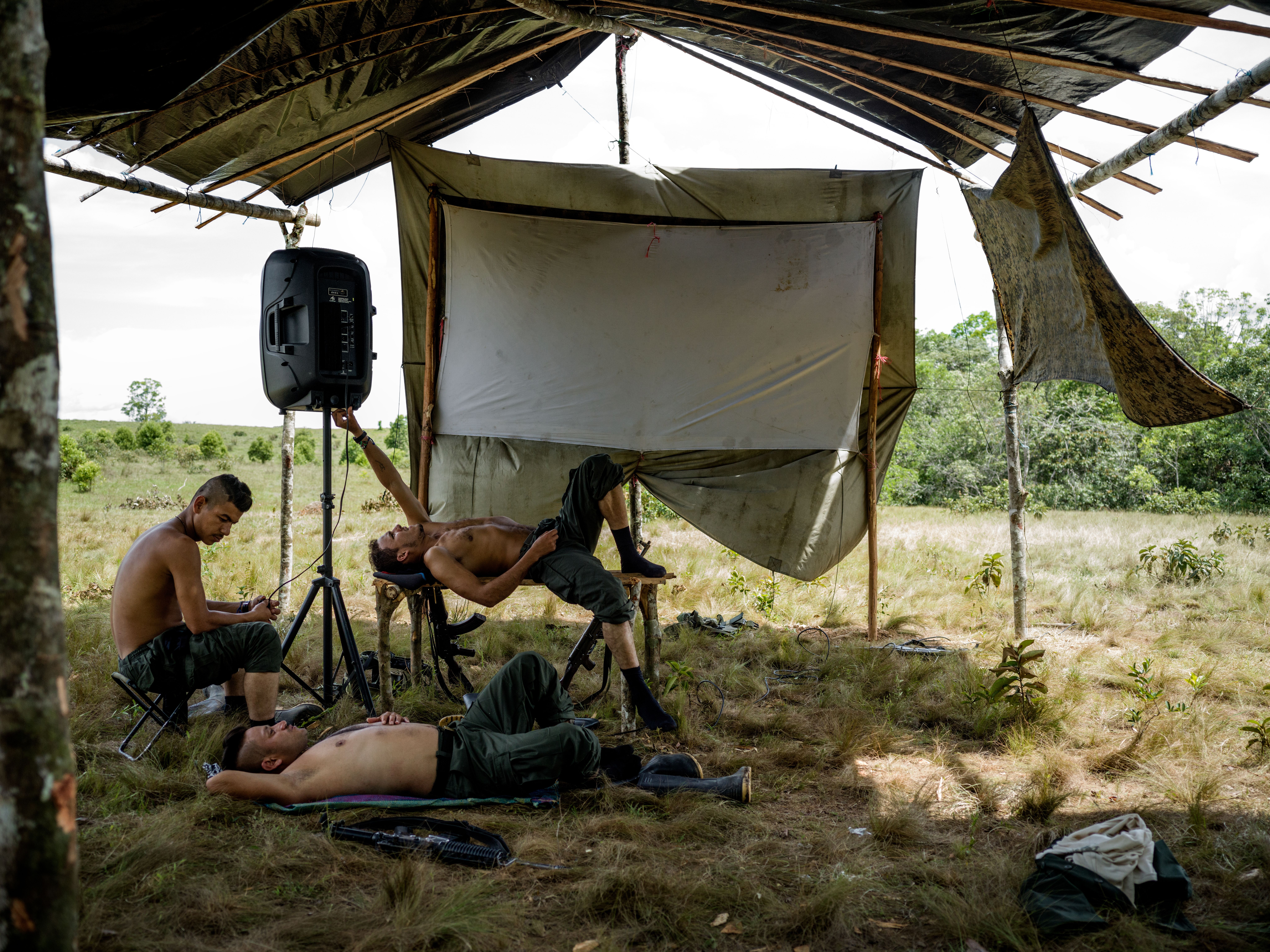 A guerilla camp in colombia with three men relaxing.