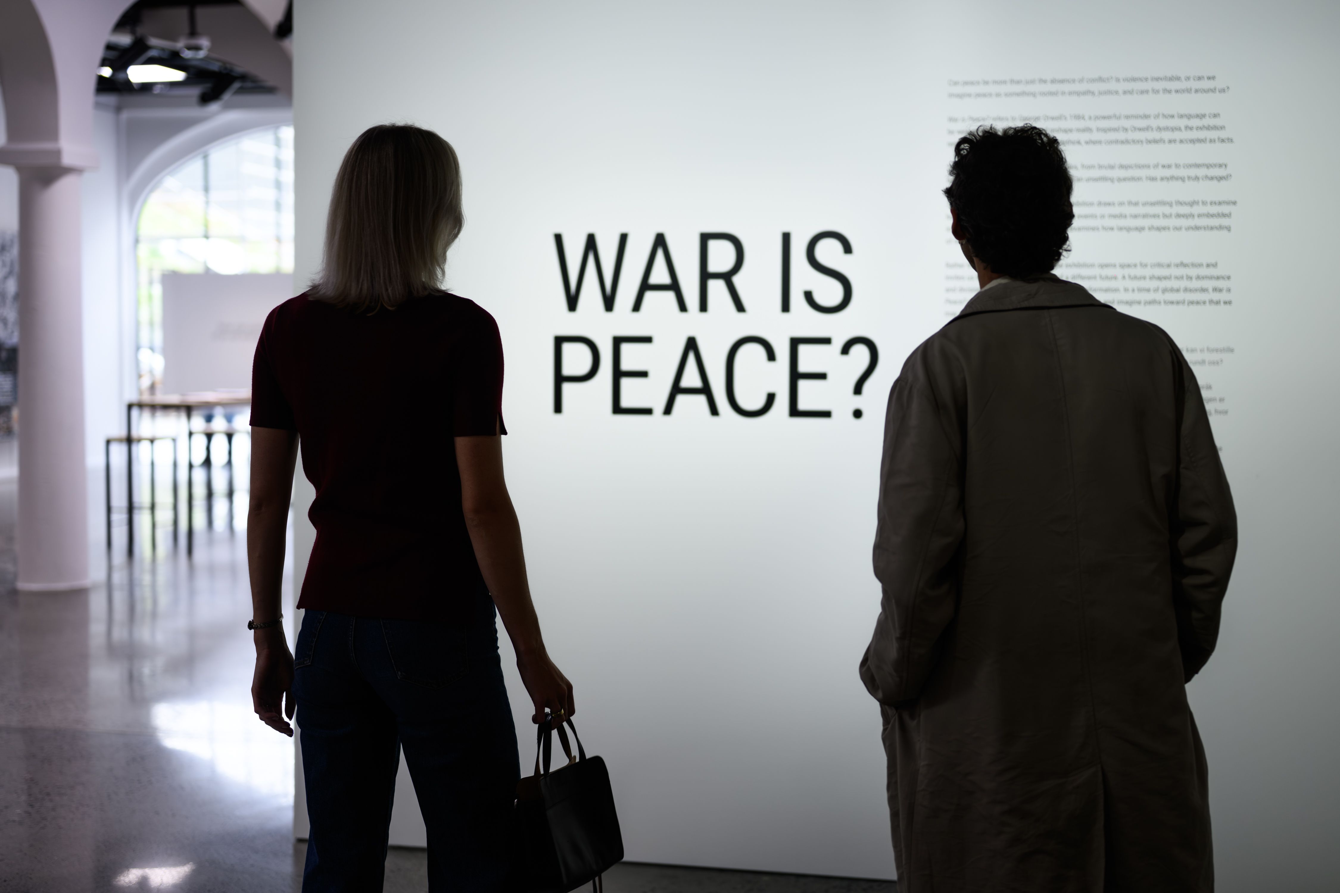 two people in front of the war is peace sign in the exhibition